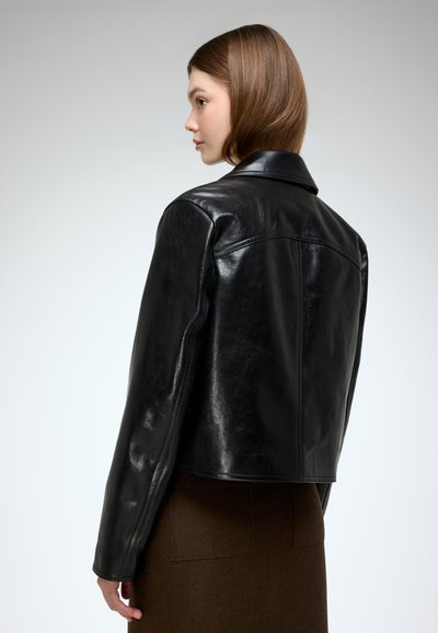 Black leather cropped jacket with a smooth texture, wide collar, and tailored shoulders. The design features minimal stitching and a fitted shape.