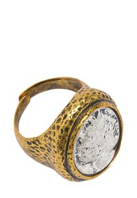 Złoty pierścionek metalowy o młotkowanej fakturze, z wyraźnym okrągłym centralnym srebrnym medalionem z misternymi detalami.