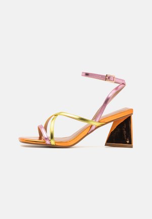Sandali a strisce metallici rosa e oro con tacco triangolare arancione e nero. Texture liscia, design open toe e cinturino alla caviglia regolabile.