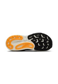 Sula av sko med en svart gummibas, vita och orange detaljer, med ett flexibelt mönster för grepp och stöd.