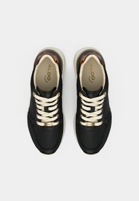 Paire de baskets basses noires avec des lacets crème, des semelles intérieures beige, des œillets dorés et des accents au talon à motif écaille, vues de dessus.