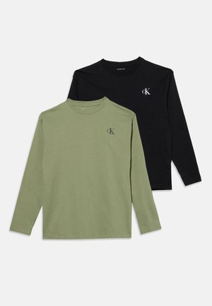 Deux t-shirts à manches longues col rond en vert olive et noir avec un petit logo "cK" sur la poitrine gauche, posés à plat sur un fond blanc.