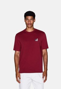 Bordeaux-rode T-shirt met korte mouwen van katoen. Bevat een klein logo op de linkerkant van de borst, met een ronde halslijn en een normale pasvorm.