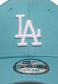 Boné de beisebol verde-água com um logotipo branco "LA" bordado. Apresenta um formato estruturado, faixa ajustável e etiqueta de marca New Era 9FORTY.
