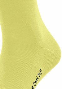 Gelbe Socke aus strukturiertem Stoff, mit geripptem Design und einem gedruckten Etikett, das in der Nähe des Zehenbereichs "Cool 24/7" liest.