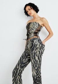 Top sin tirantes y pantalones a juego en estampado de cebra en blanco y negro. El top presenta detalles con cordones, un ajuste entallado y una tela texturizada.