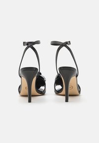 Svarte høyhælte sandaler med et elegant design, med tynne stropper, ankelstengsel og en glatt tekstur. Utsmykket med dekorative detaljer.