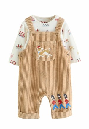 Beiger Cord-Overall für Babys mit eingesticktem Hund und drei marschierenden Wächtern, kombiniert mit einem weißen Langarmshirt mit London-Motiven.