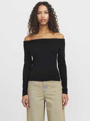 Black off-the-shoulder long-sleeve top in a ribbed texture, featuring a wide neckline and fitted silhouette. Paired with light-colored baggy jeans.
