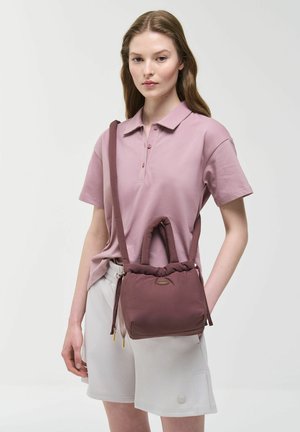 Meka torba boje bordo s jedinstvenim dizajnom ručke, izrađena od podstavljene tkanine, s zatvaračem na vezicu i malim detaljem logotipa.