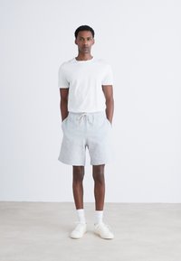 White cotton t-shirt and light gray shorts with a drawstring. The shorts are soft, relaxed fit with side pockets and smooth texture.