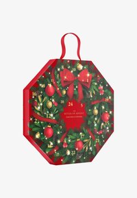Calendrier de l'Avent octogonal rouge orné de feuillage festif vert, d'ornements dorés et rouges, d'un grand nœud rouge et de portes numérotées.