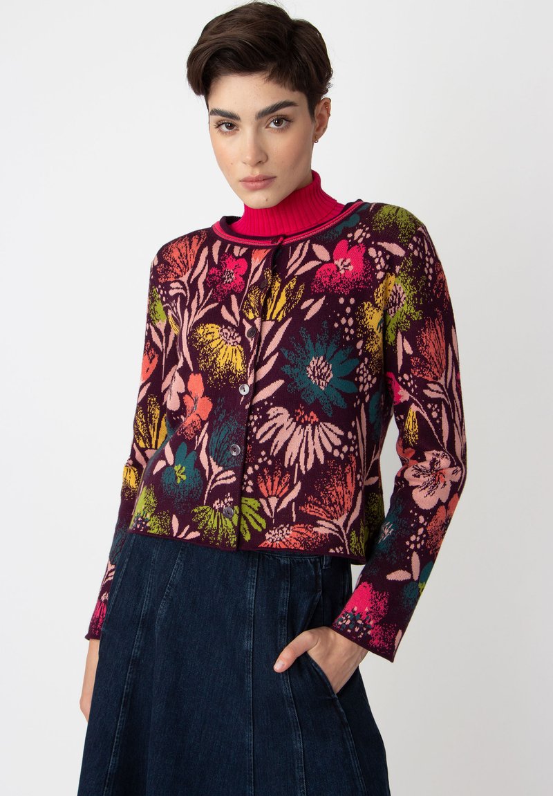 Blommig stickad cardigan i mörk lila med livfulla flerfärgade blommönster, med rund halsringning och knappstängning, strukturerad tyg.