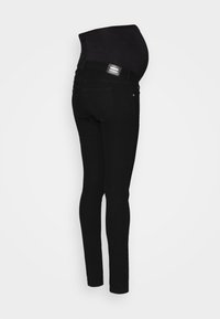 Jeans de maternidade pretos com uma cintura elástica. Design ajustado, textura suave e detalhes de costura típicos de jeans. Forma de perna justa.