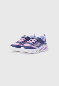 Chaussures de sport pour enfants en violet et rose avec des semelles blanches, dotées de bandes Velcro et de motifs décoratifs sur les côtés.