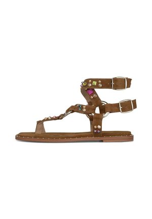 Sandalia plana marrón con correas en el tobillo y en los dedos, decorada con tachuelas multicolores y dos hebillas plateadas en las correas del tobillo.