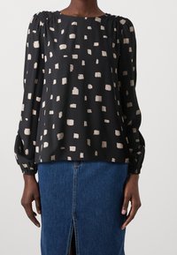 Černá blůza s krémovým abstraktním vzorem, nabraným výstřihem a dlouhými rukávy. Doplněná džínovou sukní s předním rozparkem.
