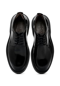 Zapatos de cuero negro con acabado brillante, forma de punta redonda, con cierre de cordones de seis ojales y un interior acolchado para mayor comodidad.