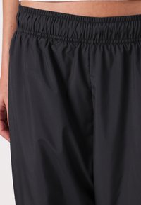 Czarne, lekkie szorty z elastycznym pasem i gładką teksturą, o prostym, nieozdobionym designie, bez widocznych kieszeni.