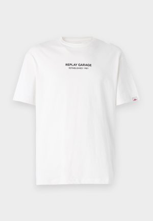 Bela bomba majica s kratkimi rokavi, na sprednji strani ima črn natisnjen logotip z napisom "REPLAY GARAGE USTVARJEN 1981".