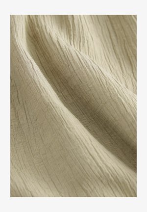 Tessuto di un beige chiaro, stropicciato, con una superficie testurizzata, che mostra sottili linee verticali e una finitura morbida e leggermente lucida.