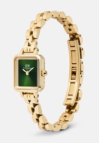 Gold-tone stainless steel wristwatch with rectangular green dial and linked bracelet, showing Daniel Wellington logo and two gold hands.