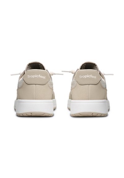 Béžové tenisky s hladkou texturou, zaobleným tvarem, bílými podrážkami a elastickými tkaničkami. Na patě se nachází logo "Tropicfeel".