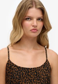 Leopardmønstret cami-top i brun og sort med tynde stropper og en afslappet silhuet. Glat stof med en let glans.