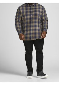 Ruudullinen nappipaita tummansinisessä, vihreässä ja beigeissä; rento malli, pitkät hihat. Yhdistetty mustiin slim fit -farkkuihin ja mustiin lenkkareihin.