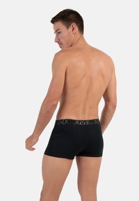 Boxer briefs neri con una cintura morbida che riporta il nome del marchio "HOM". Il materiale sembra liscio e con una vestibilità aderente, mostrando la vista posteriore.