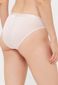 Gaiši rozā biksītes ar gludu tekstūru, aprīkotas ar mīkstu jostu, uz kuras ir iegravēts "BOSS". Klasisks hipster stils ērtībai un pielāgotībai.