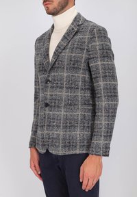 Blazer a motivo houndstooth grigio e blu, realizzato in tessuto testurizzato. Caratterizzato da colletto a rever e due bottoni frontali. Vestibilità su misura.