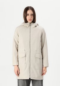 Lysbeige parka med glidelås foran, justerbar hette, to frontlommer og en jevn tekstur. Har snor ved livet.