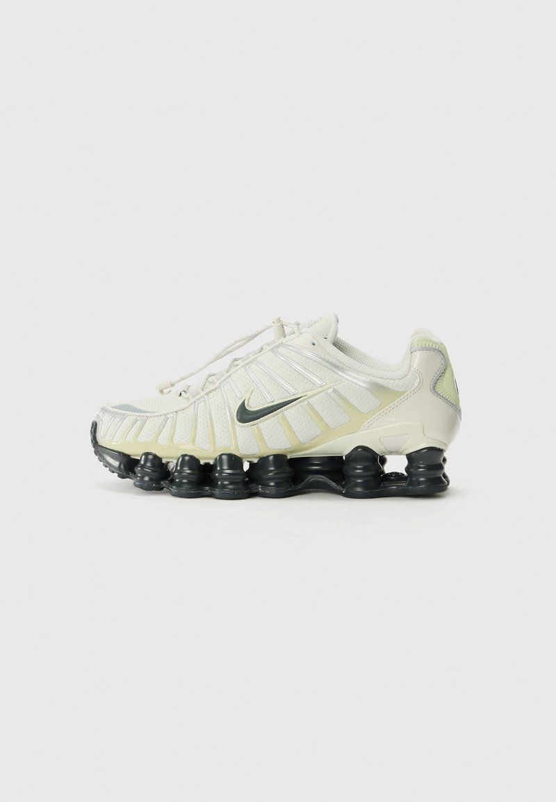 Vit och ljusgrön löparsko med mesh-överdel, svart gummi yttersula, texturerade detaljer och en distinkt segmenterad sula.