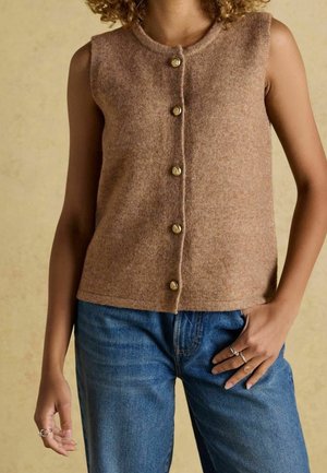 Brown sleeveless knit vest with round neckline, featuring five decorative gold buttons down the front. Worn over blue denim jeans.