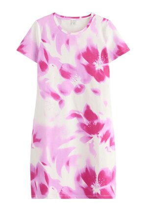 Pige smilende, stående med krydsede arme, iført en hvid og pink tie-dye kjole og røde sneakers mod en ensfarvet hvid baggrund.