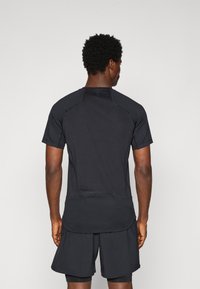 Svart treningsskjorte med korte ermer, strukturert stoff og flate sømmer. Kombinert med matchende shorts som fremhever et sporty, strømlinjeformet design.