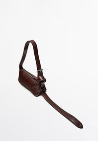 Sac bandoulière en cuir marron avec une fermeture éclair, une sangle réglable et un détail en nœud sur le côté. Texture lisse et forme rectangulaire.