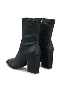 Botas de cuero negras hasta la mitad de la pantorrilla con tacones gruesos y bloques, y cremalleras laterales, mostradas en un ángulo ligero sobre un fondo blanco.