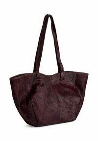 Burgundowa torba na ramię wykonana z teksturowanej skóry z włosiem, z długimi uchwytami i szerokim otwarciem, z delikatnymi detalami przeszycia wzdłuż szwów.