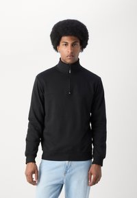 Black zip-neck sweatshirt with long sleeves and ribbed cuffs and hem. Made from a smooth material, designed for a relaxed fit.