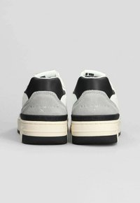 Sneakers bianche in pelle con accenti in suede grigio, tallone nero e suola in gomma a contrasto. Presentano un logo e testo in rilievo sul tallone.