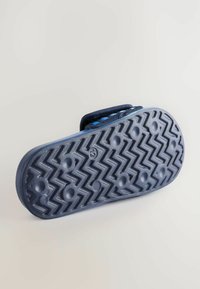 Tengeri gumitalp, texturált cikk-cakk mintázattal, körkörös tapadó pöttyökkel és enyhén kiemelkedő szélekkel. Erősített kék szövetpánt látható.