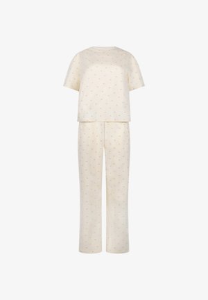 Helles, cremefarbenes Kurzarmoberteil und passender langer Hosenanzug mit subtilen, kleinen braunen Flecken auf einem weißen Hintergrund.