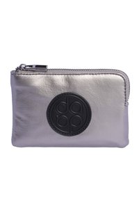 Cartera de cuero metálico plateado con un logo circular negro, cierre de cremallera y textura suave. Forma rectangular compacta con detalles de costura.