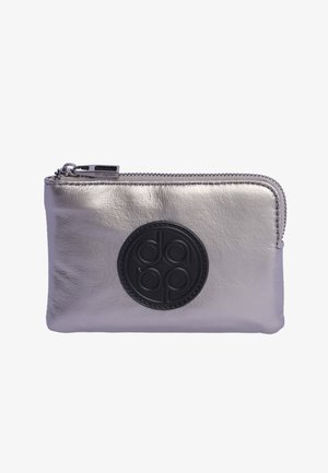 Cartera de cuero metálico plateado con un logo circular negro, cierre de cremallera y textura suave. Forma rectangular compacta con detalles de costura.