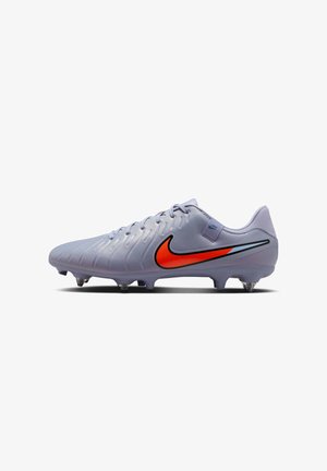 Fotbalové kopačky Nike ve světle šedé barvě, s výrazným červeným swooshem a texturovaným svrškem s tvarovanými kolíky pro lepší trakci.
