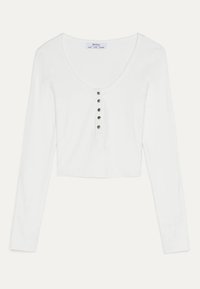 Haut court blanc à manches longues côtelé avec encolure dégagée et une rangée de cinq boutons argentés au centre devant.