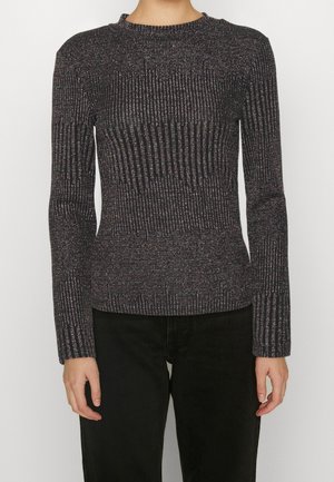 Pull ajusté à manches longues côtelé noir et gris porté avec un pantalon noir, montré du cou aux hanches sur une personne debout.