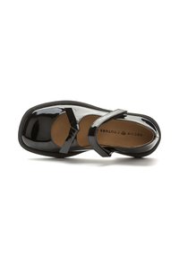 Zapato Mary Jane de charol negro con punta redondeada, correa ajustable y suela texturizada. Presenta un acabado suave y acentos mínimos.